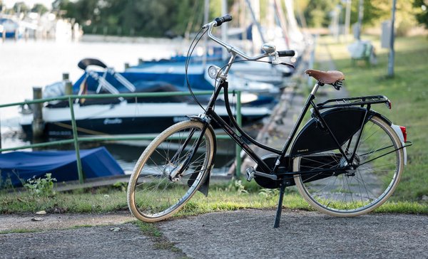 Schwarzes Hollandrad steht an einem Bootsanleger am Wasser