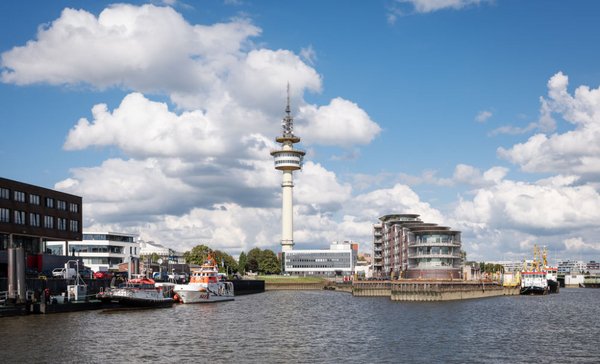 Blick auf den Bremerhavener Hafen mit dem Radarturm, Schiffen und modernen Hafengebäuden unter bewölktem Himmel