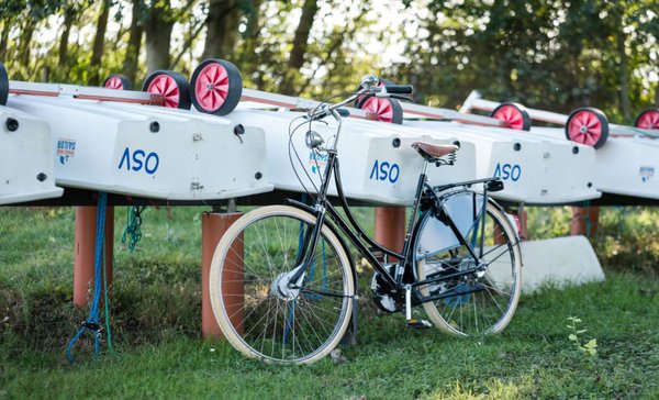 Hollandrad vor aufgebockten Segelbooten auf einer Wiese